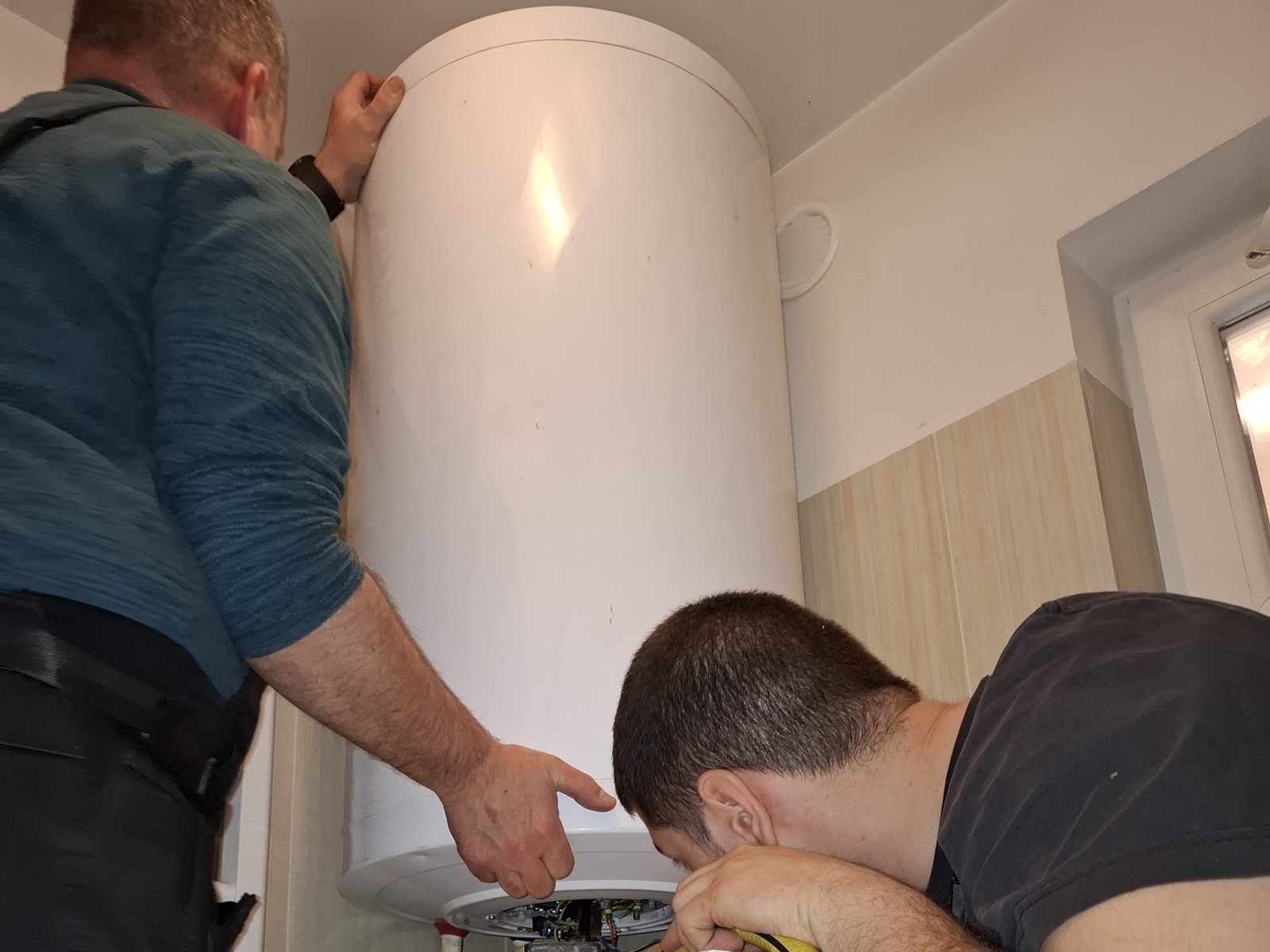 Nyári Tibor és Nyári Balázs Hajdu villanybojlert cserél egy budapesti fürdőszobában