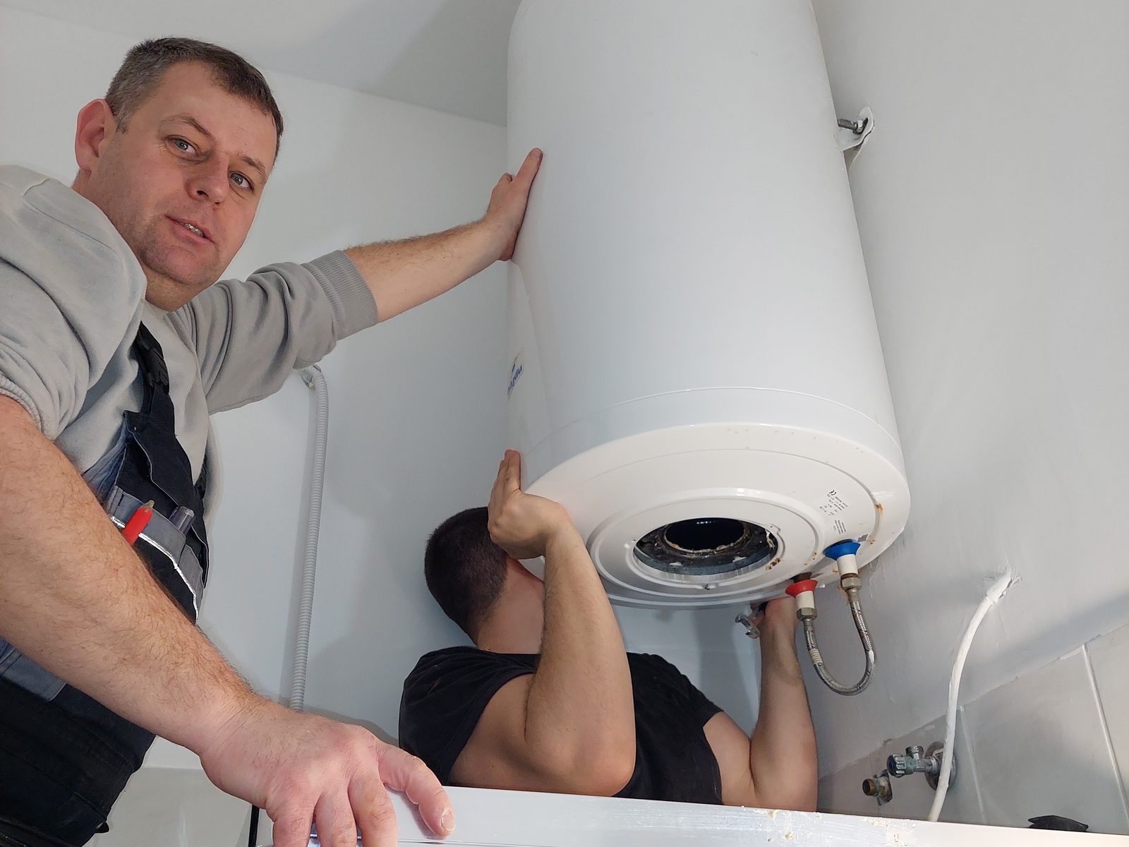 Két bojlerszerelő Hajdu villanybojlert szerel egy budapesti fürdőszobában